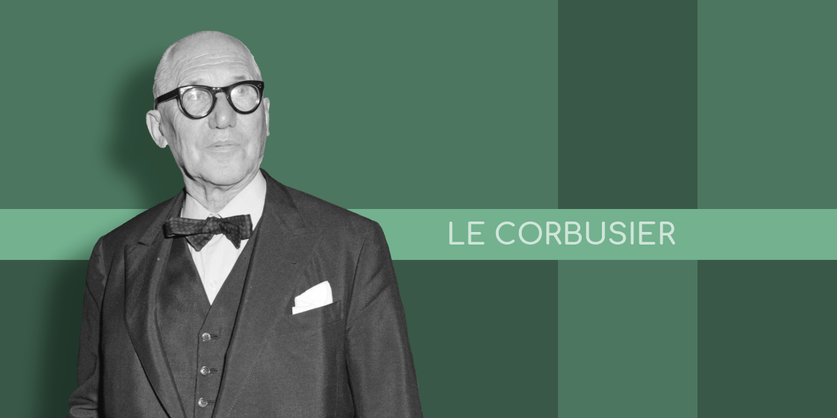 A black and white portrait of architect Le Corbusier, the creator of the Modulor system, wearing glasses, a suit, and a bow tie, standing in front of a green background.