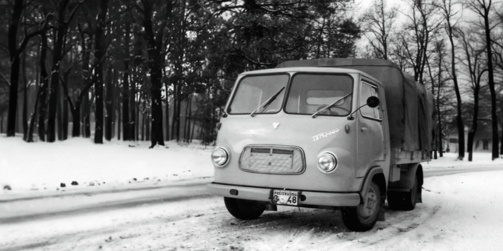 A vintage black-and-white photograph of a TAM 2000 truck, known as the Tamič Yugoslav Icon, on a snowy road with trees in the background. The truck has a single cab and a covered bed.