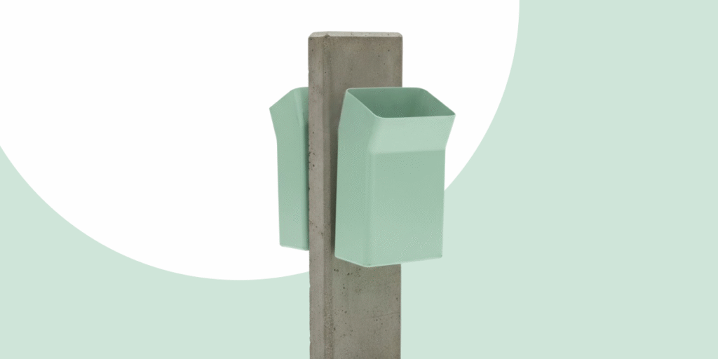 Fiberglass Frog trash bin by Saša Mächtig, mounted on a concrete post with minimalist green background.