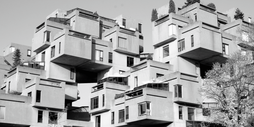 Black and white view of Habitat 67 in Montréal with stacked concrete housing units and private terraces.